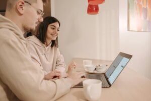two people stand in front of a laptop